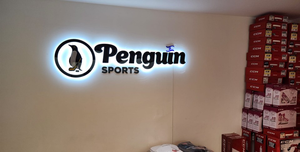 Illuminated Penguin Sports logo inside the Ra'anana store